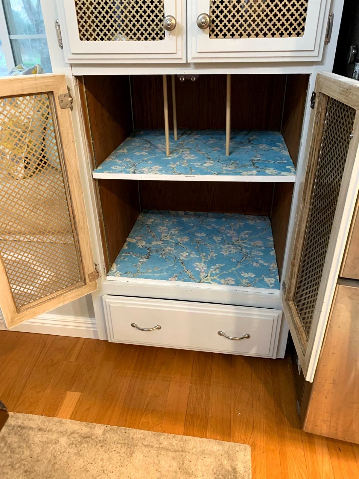 Custom cabinet storage for baking trays and pans lined with leftover blue Almond Blossom wallpaper