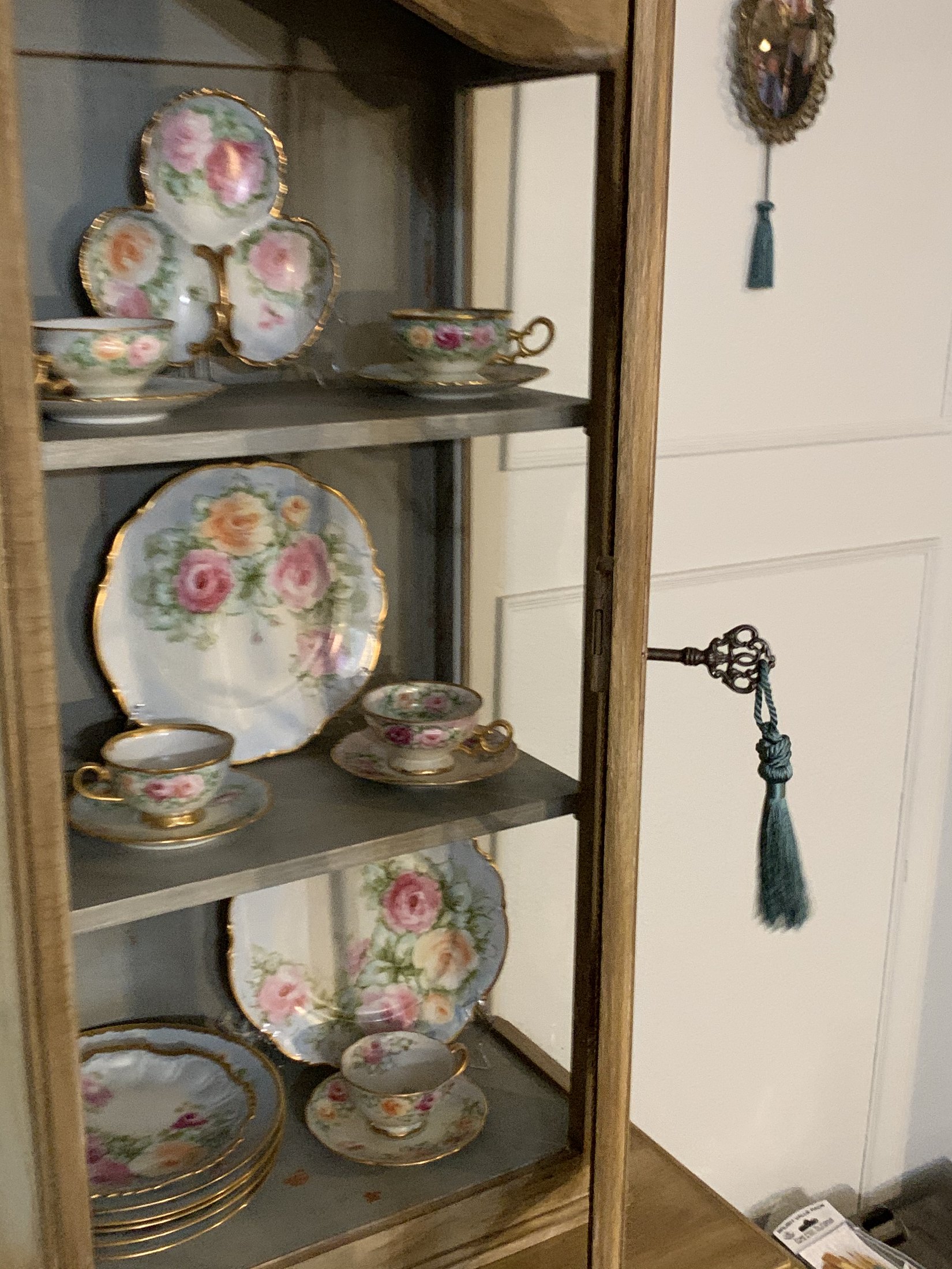 Detail of the inherited hand-painted dishes displayed inside the cabinet