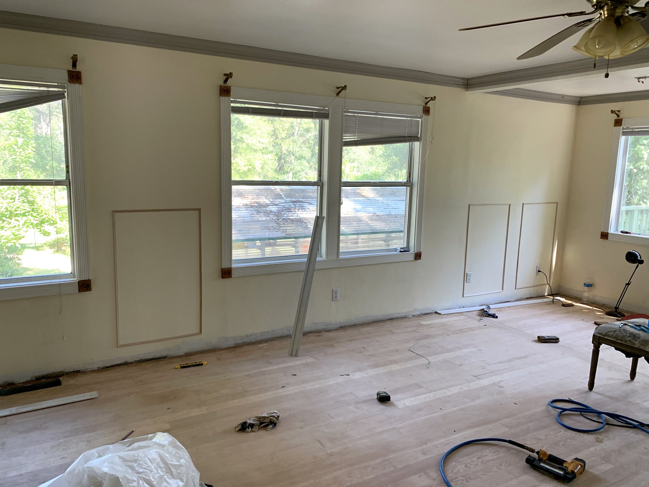 Living room with sanded hardwood floor and wall-panel layout in progress