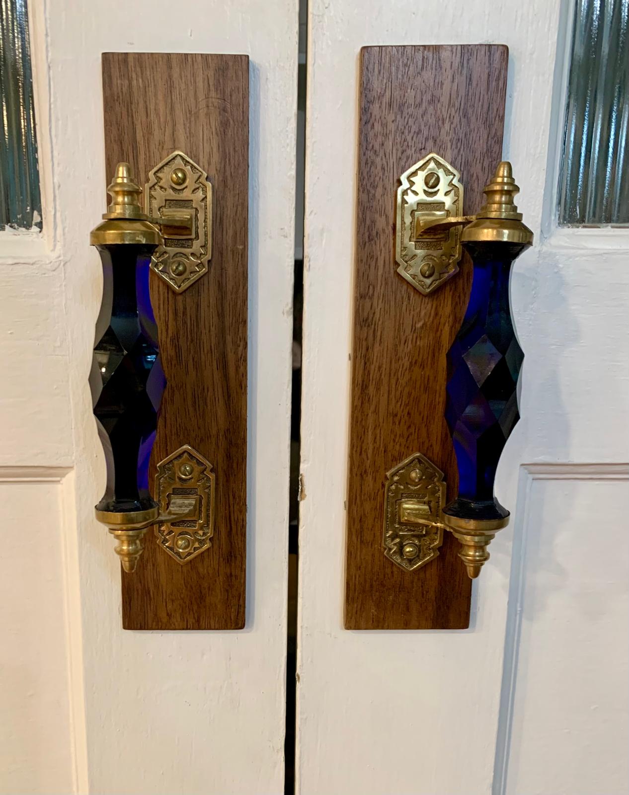 Large cobalt-blue glass pantry-door handles mounted on walnut backplates with aged brass fittings
