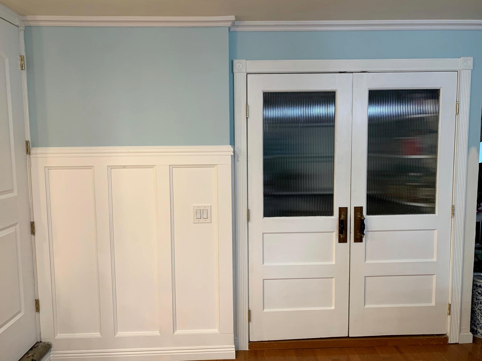 Finished antique pantry doors integrated into the paneled entry wall
