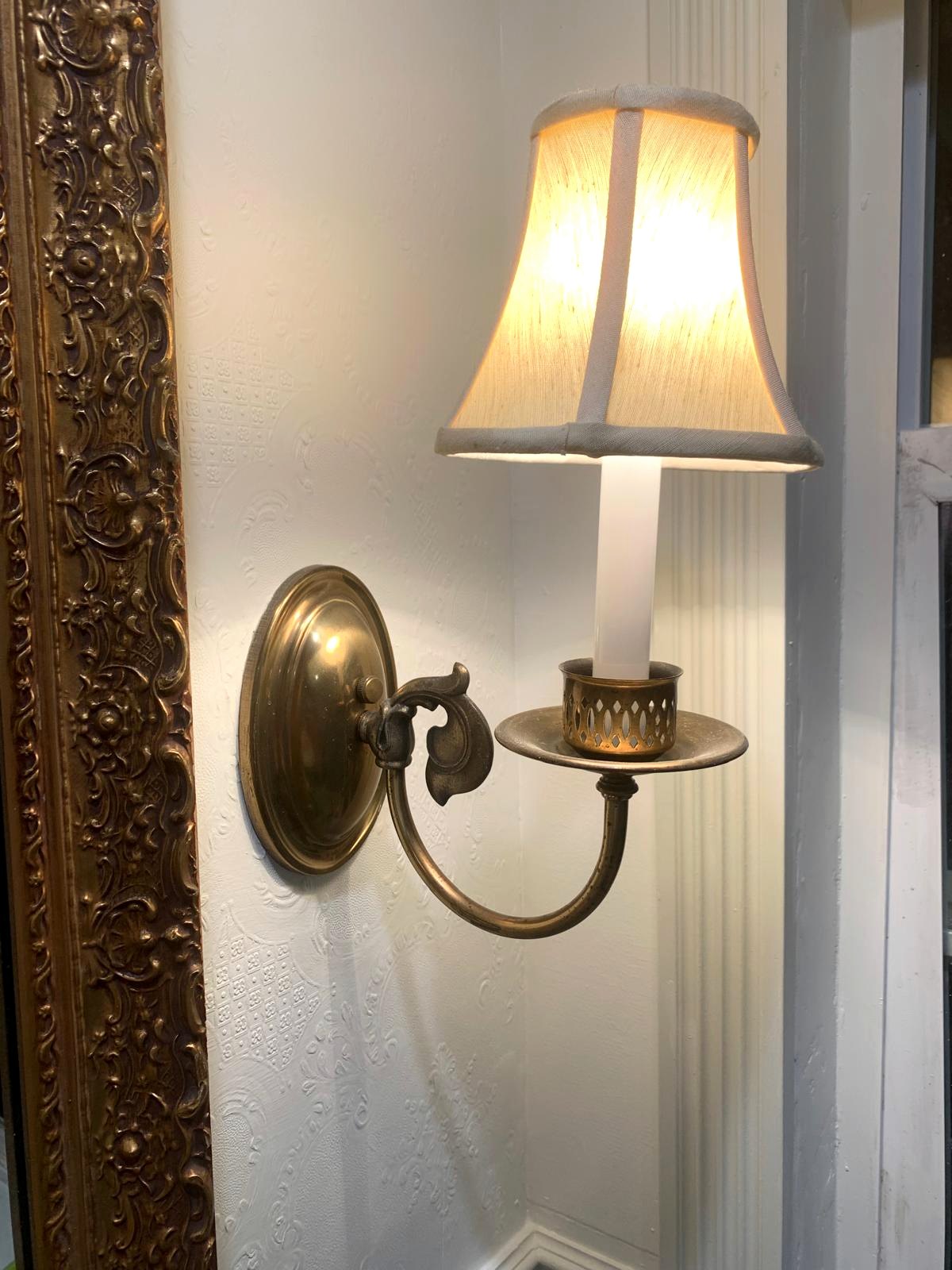 Antique brass wall sconce beside the ornate framed mirror in the Victorian-inspired bathroom