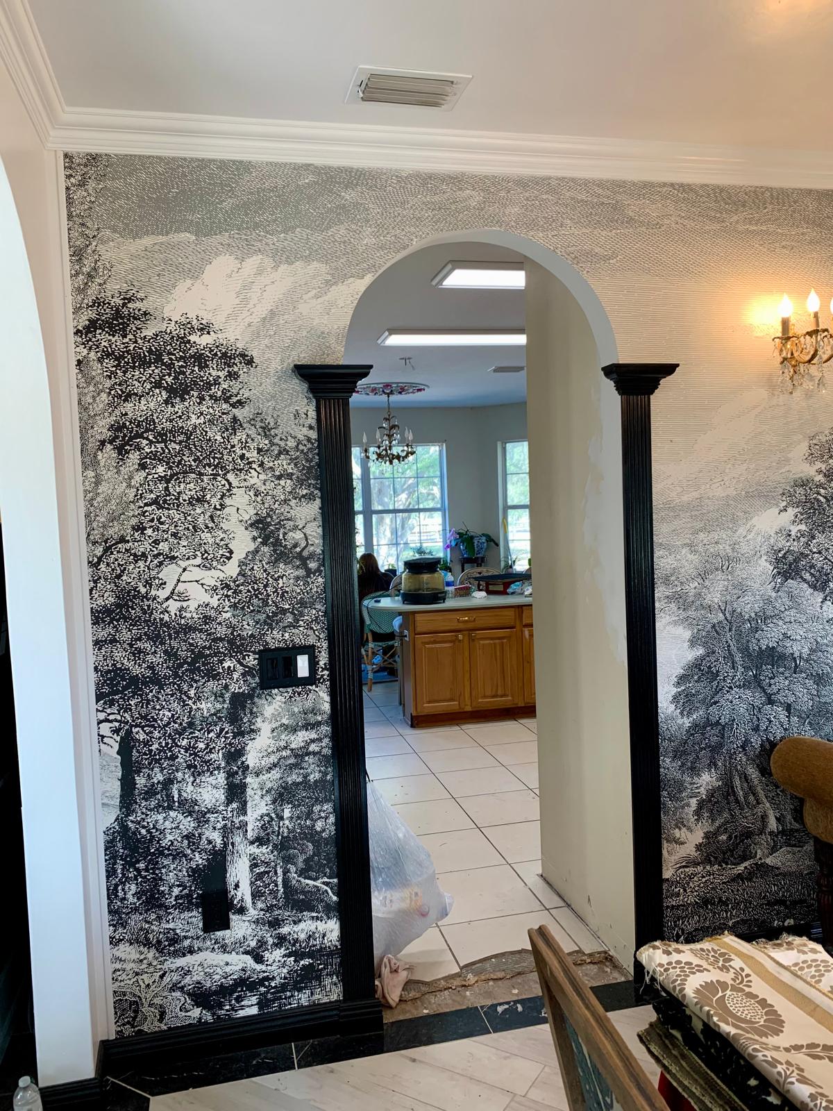 Scenic mural wrapping around a newly formed arched opening with layered black millwork